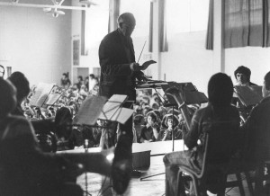 John conducts one of his music groups at a school assembly, Jan 1977